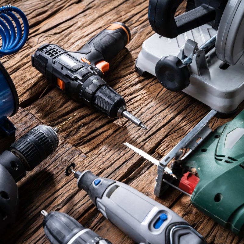 Various Power Tools Laying On Wooden Desk